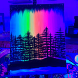 Painting of a forest silhouette with a rainbow background on an easel.